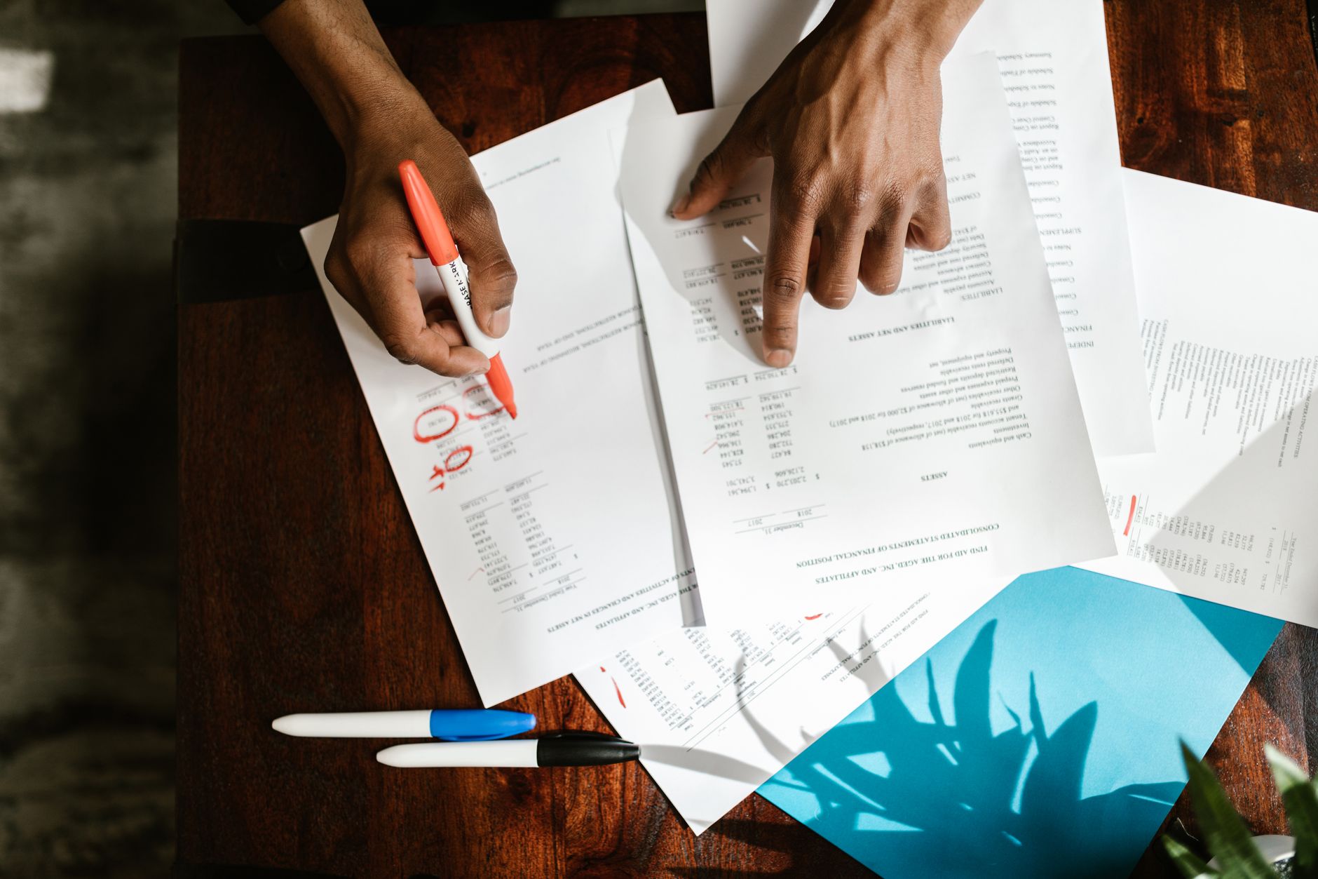 Overhead view of hands highlighting financial documents on a desk; stock image for preparing cost and insurance questions.